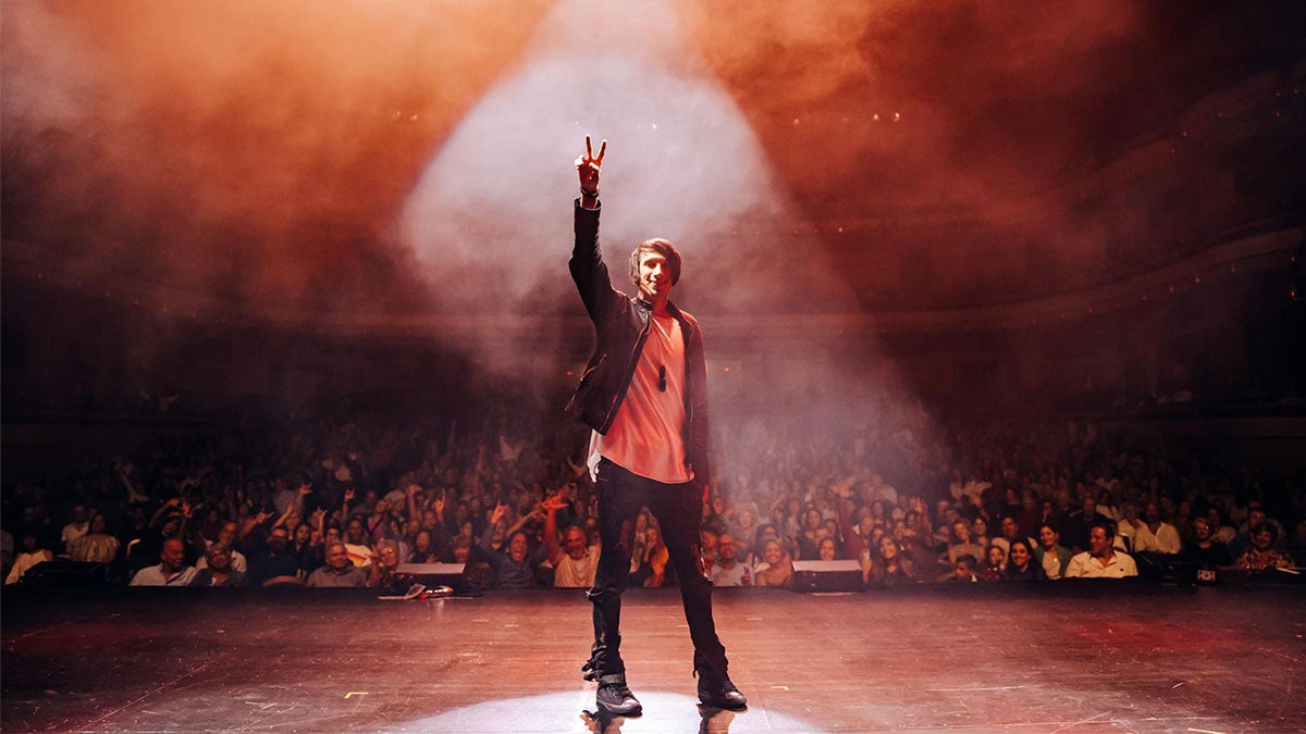 Reza on stage with crowd in background at Reza Edge of Illusion Show
